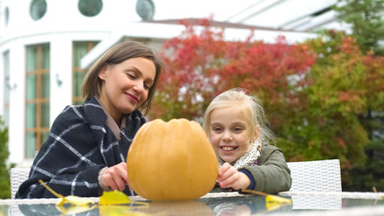 Fototapeta premium Mother helping child to carve pumpkin Jack for Halloween, autumn party, fun