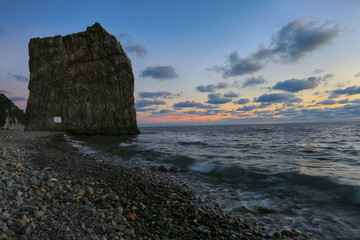Evening sky, rock in the form of a sail, sea and clouds