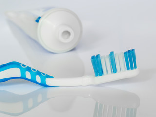 Blue toothbrush on a white glossy background. The concept of daily dental care, oral hygiene, prevention of diseases of the teeth and gums, health care.