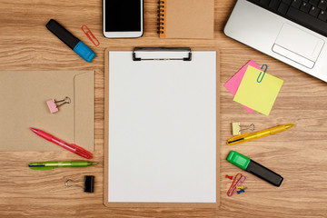 Clipboard with office supplies on wooden table, top view