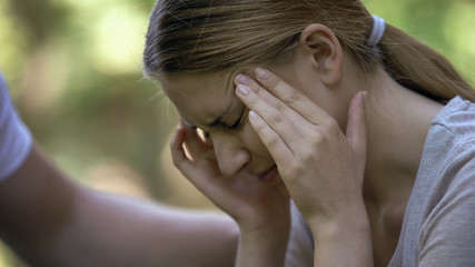 Girl suffering acute headache, worrying about failures, male hand comforting her