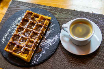 Cup of coffee and Belgian waffles with chocolate