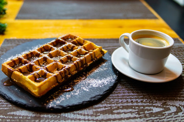 Cup of coffee and Belgian waffles with chocolate