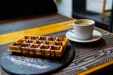 Cup of coffee and Belgian waffles with chocolate