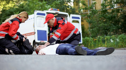 Doctors providing urgent care to unconscious man, heart attack or car accident