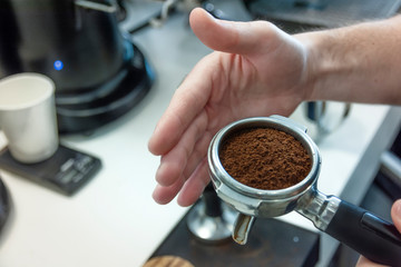 Fototapeta na wymiar Barista presses ground coffee in the spoon