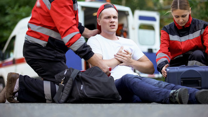 Paramedics caring for man suffering from chest pain, qualified medical care