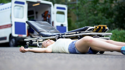 Unconscious girl lying near stretcher, victim of road accident or disaster © motortion