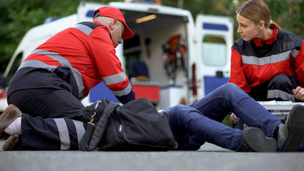 Paramedics helping patient on road, first aid trainings, medical qualification © motortion