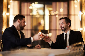 Portrait of two business partners drinking whiskey in restaurant celebrating successful deal, copy space
