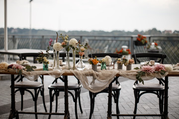 A table with a tablecloth and a lots of flowers in pots on it.