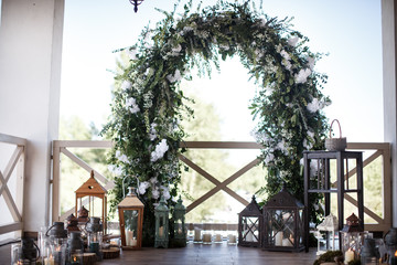 A big flower arch with a bunch of burning lanters alongside it.