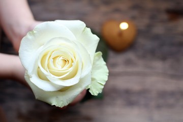 Naklejka premium Child boy holds flower in your hand. Cookie with a lit candle. Heart cookie. Birthday concept. About love.