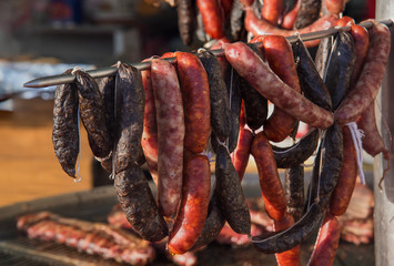 Different kinds of fresh spanish sausages hanging in bunches on the marketplace. Soft focus.10