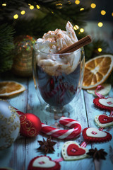 Low key christmas composition with thermo glass cup of tasty coffee topped with frothy milk and cinnamon powder served on rustic wooden table with xmas decoration 2