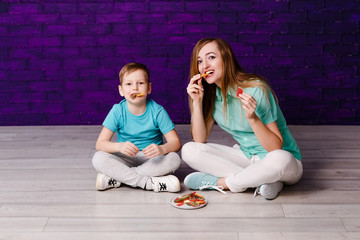 young long-haired mother and seven-year-old child eating colored marmalade