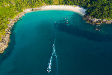 View from above, aerial view of a beautiful tropical beach with white sand and turquoise clear water, longtail boats and people sunbathing, Freedom beach, Phuket, Thailand.