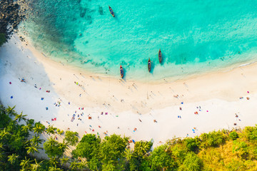 View from above, aerial view of a beautiful tropical beach with white sand and turquoise clear water, longtail boats and people sunbathing, Freedom beach, Phuket, Thailand.