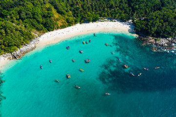 View from above, aerial view of a beautiful tropical beach with white sand and turquoise clear water, longtail boats and people sunbathing, Freedom beach, Phuket, Thailand.