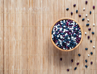 Colorful beans in a wooden bowl on a bamboo napkin