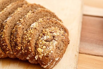 Rye bread with grains of cereals on a wooden stand on a wooden background with space for text