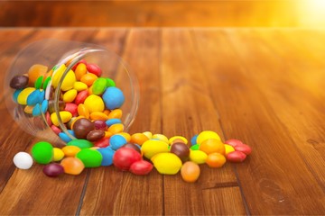 Colorful candies sweets falling out of a glass jar, composition isolated over the white background