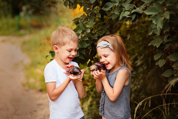 cute happy-haired fair-haired children boy and girl 5-6 years old with snails aha-tin in their arms laughing and showing malyosks