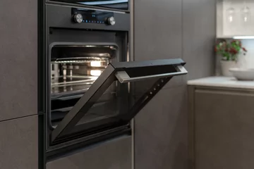 Foto op Plexiglas Open door on new built-in oven in black kitchen cabinet © brizmaker