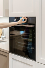Woman hand switch program on control panel built-in oven