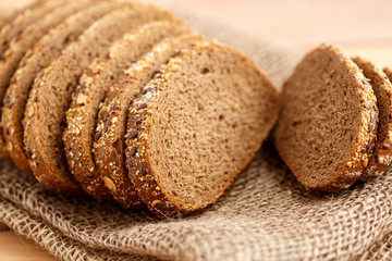 Rye bread with grains of cereals on canvas on a wooden background with space for text