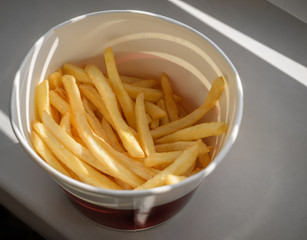 French fries in a paper cup. Selective focus and shallow depth of field.