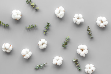 Flowers composition on gray desk with eucalyptus branches and cotton. Flat lay, top view, copy space