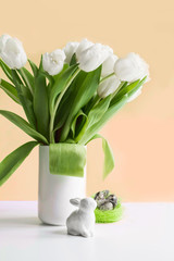 Easter. White tulips in vase, bunny, white eggs on pastel.