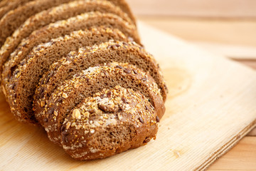 Rye bread with grains of cereals on a wooden stand on a wooden background with space for text