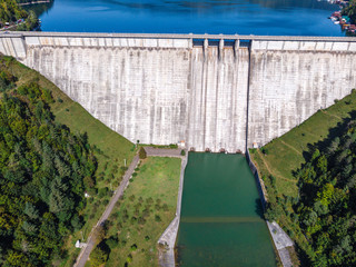 Aerial scenic view of a dam constructed on a beautiful valley in mountains. water storage reservoir. road with beautiful views for travel and holidays. lake Lzvorul Muntelui, Romania.