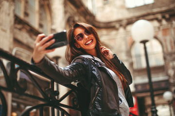 Young happy woman taking selfie on the street in the city