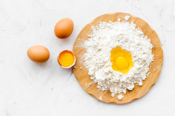 Baking background with eggs and flour on white desk. Top view.
