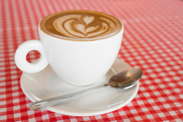 Coffee cup placed on red and white patterned fabric