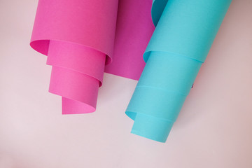 A sheet of paper blue and pink rolled into a tube on a light background.