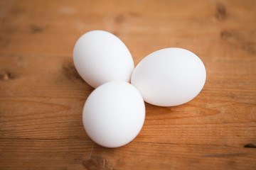 Three white eggs on a wood ground