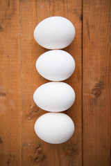 Four white eggs in a raw on a wood ground