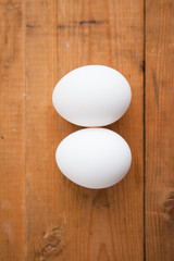 Two white eggs on a wood ground