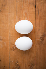 Two white eggs on a wood ground