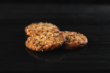 Oatmeal cookies with seeds, sesame seeds on a black background with reflection