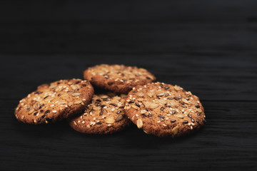 Oatmeal cookies with seeds, sesame seeds on black wooden background