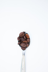 Coffee beans in the spoon on a white ground