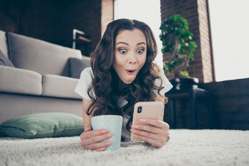 Close up photo funny funky beautiful brunette she her lady telephone hands arms hot beverage reader letter wearing domestic light color t-shirt pants clothes outfit lying carpet pillow floor divan