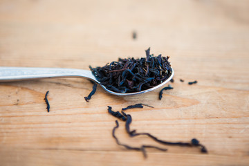 Tea leaves in spoon on a wood ground