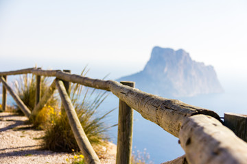 Wooden railing in a mountain path, the viewpoint of Morro de Toix, Penon of Ifach in Calpe is in the background