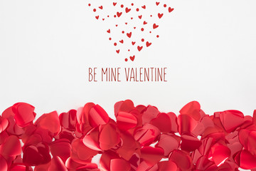 close-up view of beautiful red heart shaped petals on grey background with "be mine valentine" lettering